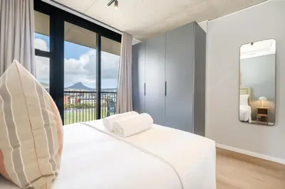 a bedroom with a white bed and a large window at Riverlands - Mountain View 1-BR Premium Apartment in Cape Town