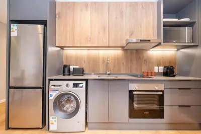 a kitchen with a refrigerator and a washing machine at Riverlands - Mountain View 1-BR Premium Apartment in Cape Town