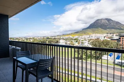 a balcony with a table and chairs and a mountain at Riverlands - Mountain View 1-BR Premium Apartment in Cape Town