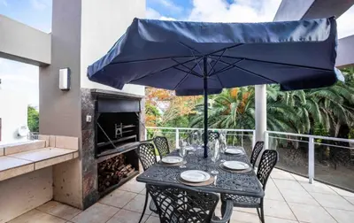 a dining table with an umbrella on a patio at Akasia 1 in Caledon