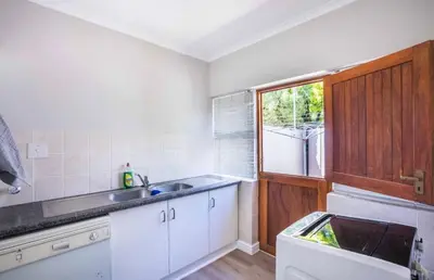 a kitchen with white cabinets and a sink and a window at Akasia 1 in Caledon