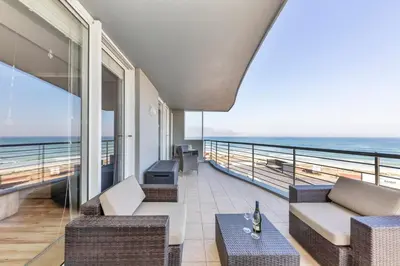 a room with a balcony with a view of the ocean at Horizon Bay 201-Beachfront Gem Table Mtn in Cape Town