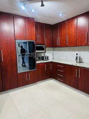 a kitchen with wooden cabinets and a person standing in it at Surrey B&B in Surrey Estate