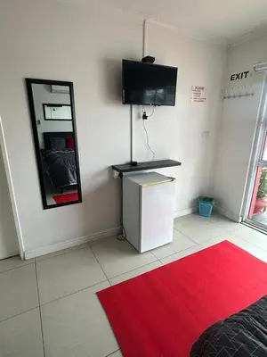 a room with a red rug and a tv on the wall at Surrey B&B in Surrey Estate