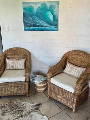 two wicker chairs sitting next to a wall at Pebbles & Shells in Kleinmond