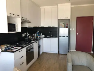 a kitchen with white cabinets and a refrigerator at Cape on Porterfield in Cape Town
