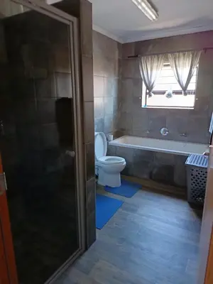 a bathroom with a toilet and a tub and a window at Bluehaven self-catering guesthouse in Hermanus