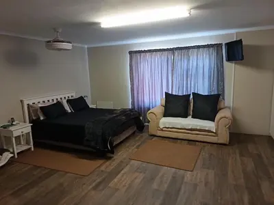a bedroom with a bed and a couch and a window at Bluehaven self-catering guesthouse in Hermanus
