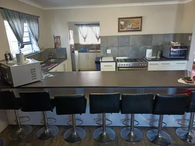 a kitchen with a counter with bar stools at Bluehaven self-catering guesthouse in Hermanus