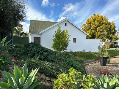 a white house with a landscaping at Rose Garden, a Self-catering cottage in Worcester