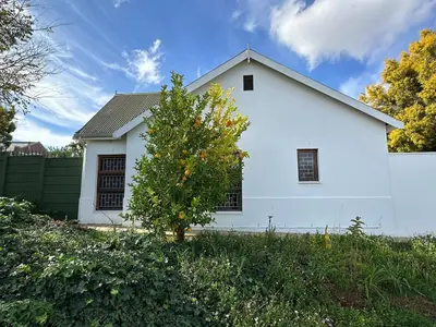 a white house with a tree in front of it at Rose Garden, a Self-catering cottage in Worcester