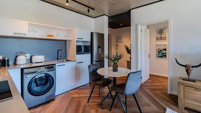 a kitchen with a washing machine and a table at The Bridgewater collection 411- Luxury 1 bed Morden Apartment at Century City in Cape Town