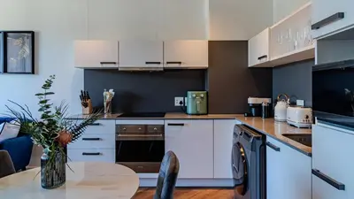 a kitchen with white cabinets and a table at The Bridgewater collection 411- Luxury 1 bed Morden Apartment at Century City in Cape Town