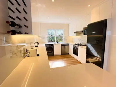 a kitchen with white cabinets and black appliances at Peach On Beach Boutique Apartments in Hermanus