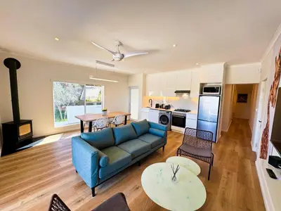a living room with a blue couch and a kitchen at Peach On Beach Boutique Apartments in Hermanus