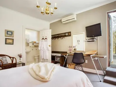 a bedroom with a bed and a desk and a television at The Residence Boutique Hotel in Grabouw