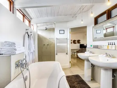 a bathroom with two sinks and a tub and a shower at The Residence Boutique Hotel in Grabouw