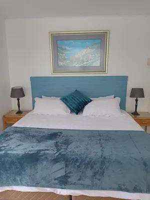 a large bed with a blue headboard and two lamps at Mountain View in Hermanus