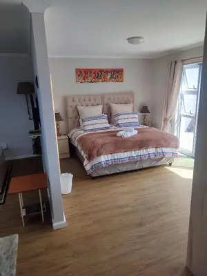 a bedroom with a large bed and a window at Birds Holiday Accommodation 1 in Zeekoevlei