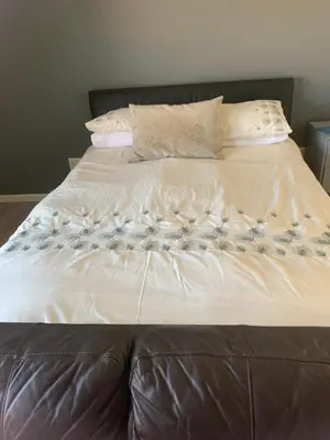 a large bed with a brown leather headboard and pillows at Western Cape in Cape Town