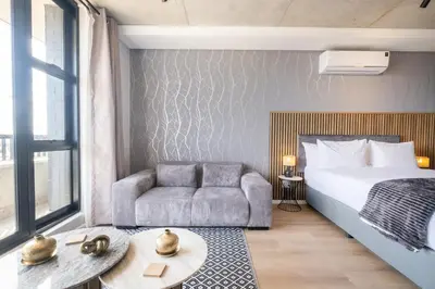 a bedroom with a bed and a couch and a table at 507 Riverlands - Lux Studio Apartment in Cape Town