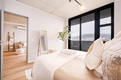 a bedroom with a large white bed and large windows at 705 Riverlands - 1Bedroom Apartment with Mountain Views in Cape Town