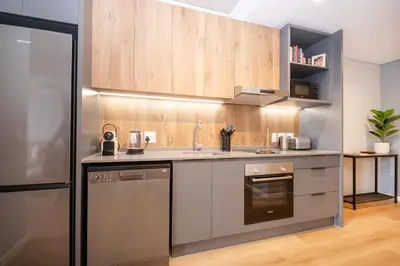 a kitchen with stainless steel appliances and wooden cabinets at 705 Riverlands - 1Bedroom Apartment with Mountain Views in Cape Town