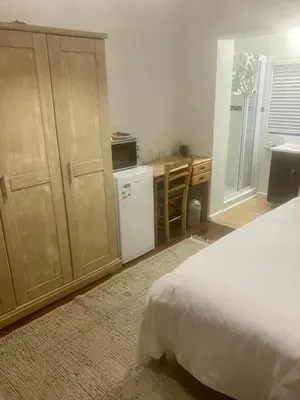 a bedroom with a bed and a desk and a refrigerator at Conde Rest in Stellenbosch