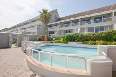 a swimming pool in front of a building at 2 Bedroom Apartment - Dolphin Beach in Cape Town
