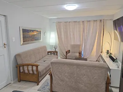 a living room with a couch and a chair at Blouberg 2 bedroom apartment in Cape Town
