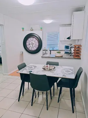a dining room table with chairs and a clock on the wall at Blouberg 2 bedroom apartment in Cape Town