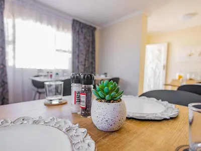 a table with plates and a potted plant on it at Olive Grove Bed & Breakfast in Kraaifontein