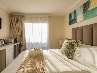 a bedroom with a large bed with a window at Olive Grove Bed & Breakfast in Kraaifontein