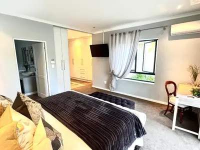 a bedroom with a bed and a desk and a window at 10onErika Franschhoek in Franschhoek