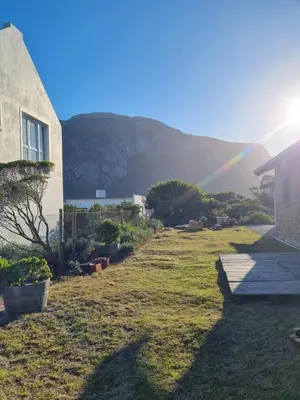 a rainbow in the sky over a yard with a house at Heaven Scent in Bettyʼs Bay
