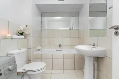 a white bathroom with a toilet and a sink at La Savina The Island Club in Cape Town