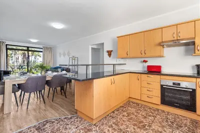 a kitchen with wooden cabinets and a table with chairs at La Savina The Island Club in Cape Town