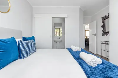 a bedroom with a large white bed with blue pillows at La Savina The Island Club in Cape Town