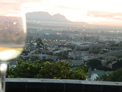 a glass of wine overlooking a city at sunset at 43 On Sandstone in Somerset West