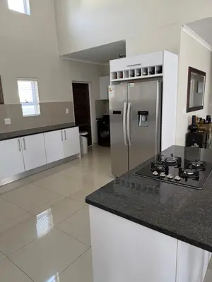a kitchen with a stainless steel refrigerator and white cabinets at Parklands Family Stay in Cape Town
