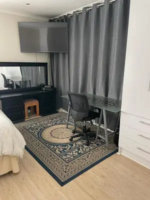 a bedroom with a desk and a chair on a rug at Parklands Family Stay in Cape Town
