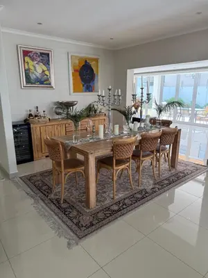 a dining room with a table and chairs on a rug at Parklands Family Stay in Cape Town