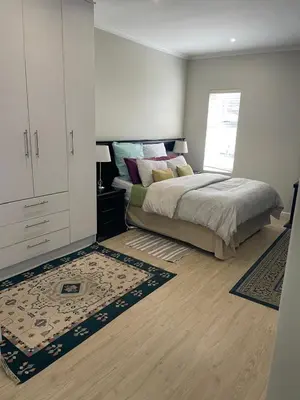 a bedroom with a bed and a cabinet and a rug at Parklands Family Stay in Cape Town