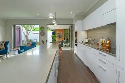 a kitchen with white cabinets and a living room at Luxury Villa in Best Central Location in Franschhoek