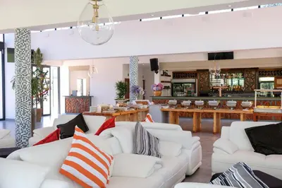 a living room with white couches and tables at Houw Hoek Hotel in Botrivier