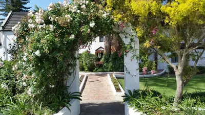 a garden with a white arch covered in flowers at Houw Hoek Hotel in Botrivier