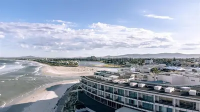 a view of a beach with a building and the ocean at Beautiful Views - Lagoon Beach 2 Bed Apartment in Cape Town