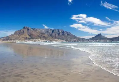 a view of the beach with a mountain in the background at Beautiful Views - Lagoon Beach 2 Bed Apartment in Cape Town
