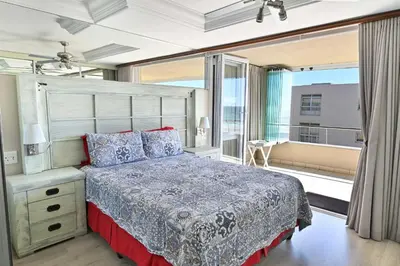 a bedroom with a large bed and a balcony at Beautiful Views - Lagoon Beach 2 Bed Apartment in Cape Town