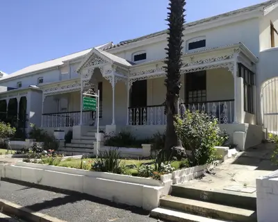 a white house with a palm tree in front of it at House On Plein in Paarl
